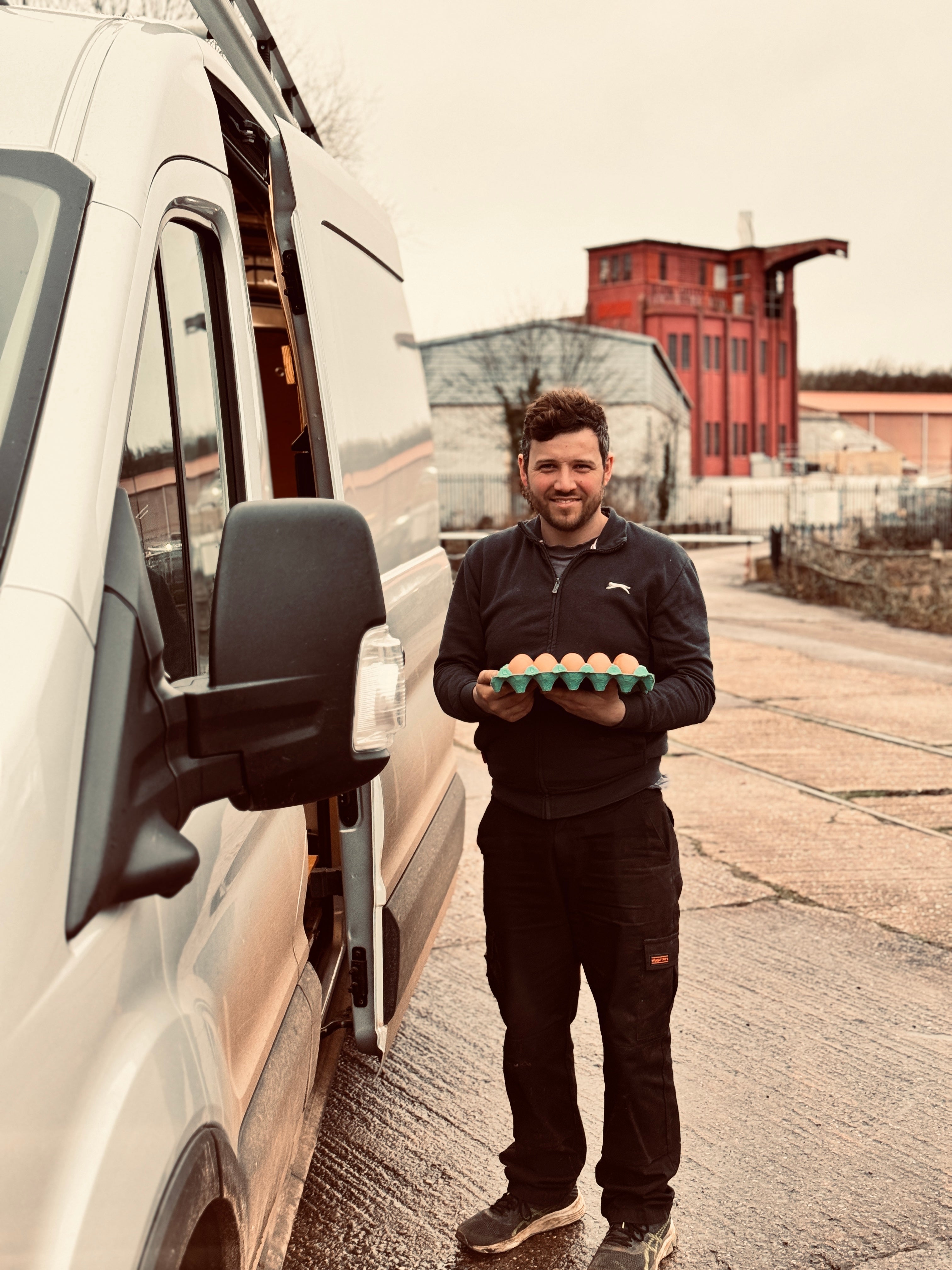 Adam holding a tray of Appledore Farm eggs beside the delivery van